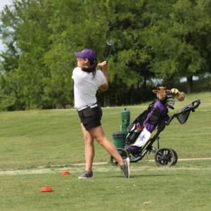 An HSU female golfer swinging.